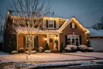 Maison de banlieue décorée de guirlandes LED blanches chaudes en hiver avec neige légère au sol