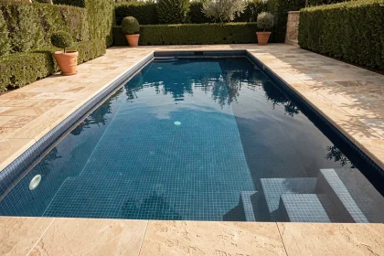 Piscine extérieure avec revêtement en mosaïque bleue et margelles en pierre naturelle