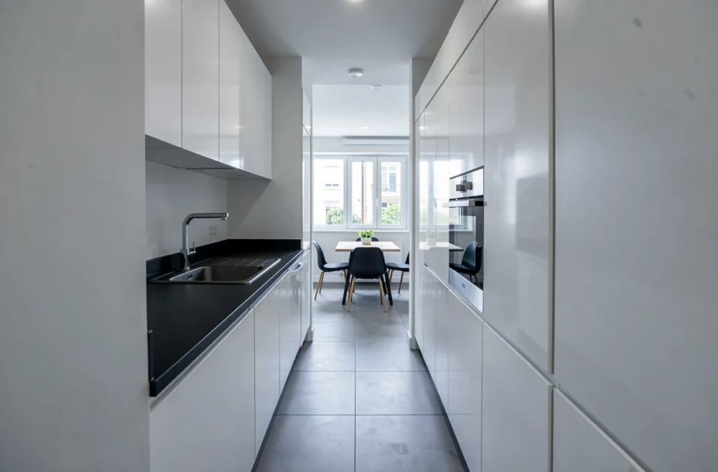 Cuisine en couloir aménagée par SRM à Drancy avec façades blanches laquées et plan stratifié noir